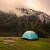 Tent set up outdoors with mountains in background, showcasing adventure and nature.
